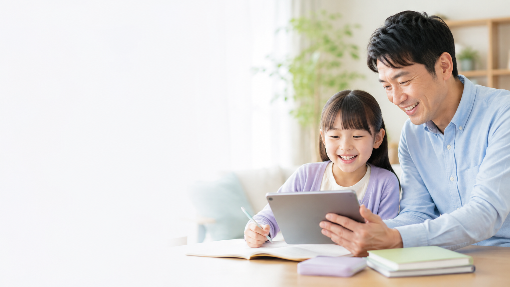 家庭でタブレットを見ながら笑顔で学ぶ親子
