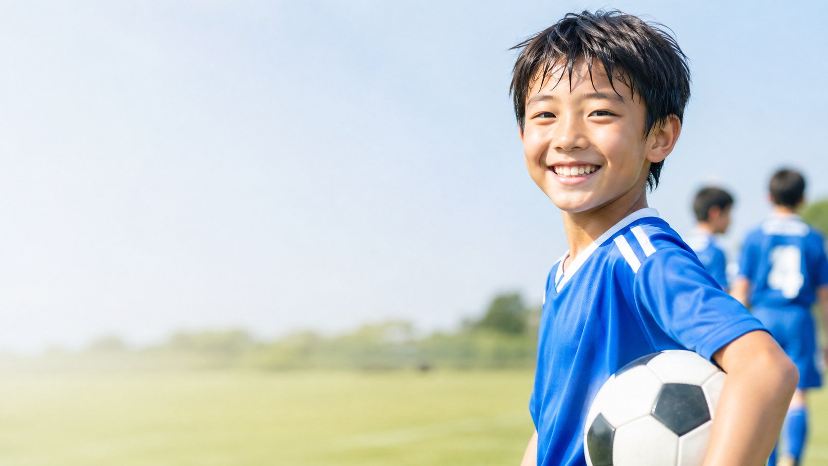 サッカーグラウンドで笑顔を見せる小学生男子